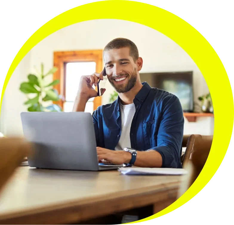 man sitting at desk talking on the phone and using laptop